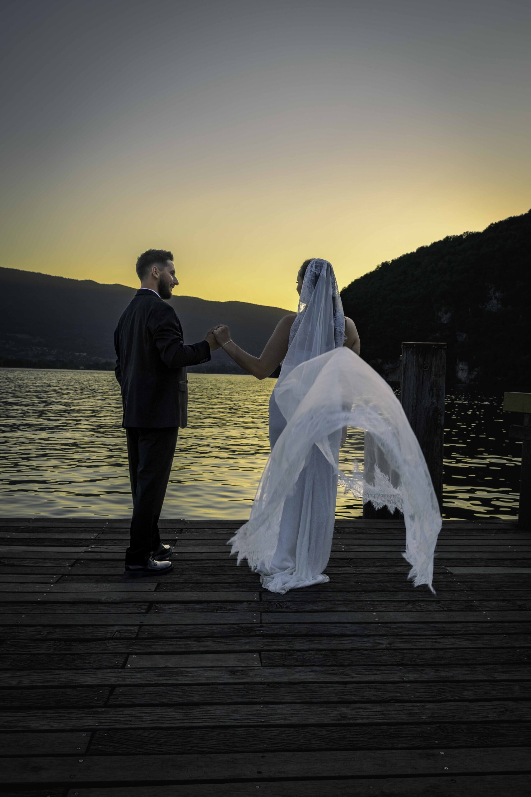 Couple de jeunes mariés admirant le coucher de soleil sur le lac d'Annecy à Talloires – séance photo mariage